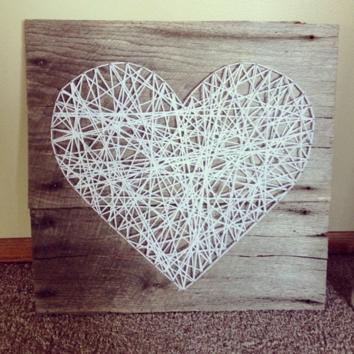 ein weißes Herz aus Fäden, braunes Brettchen, eine romantische Deko am Valentinstag, 