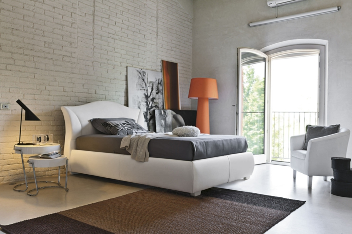 eine ausgefallene Schlafzimmer Deko mit schwarz weißes Bild, graues Bett, ein bunter Teppich