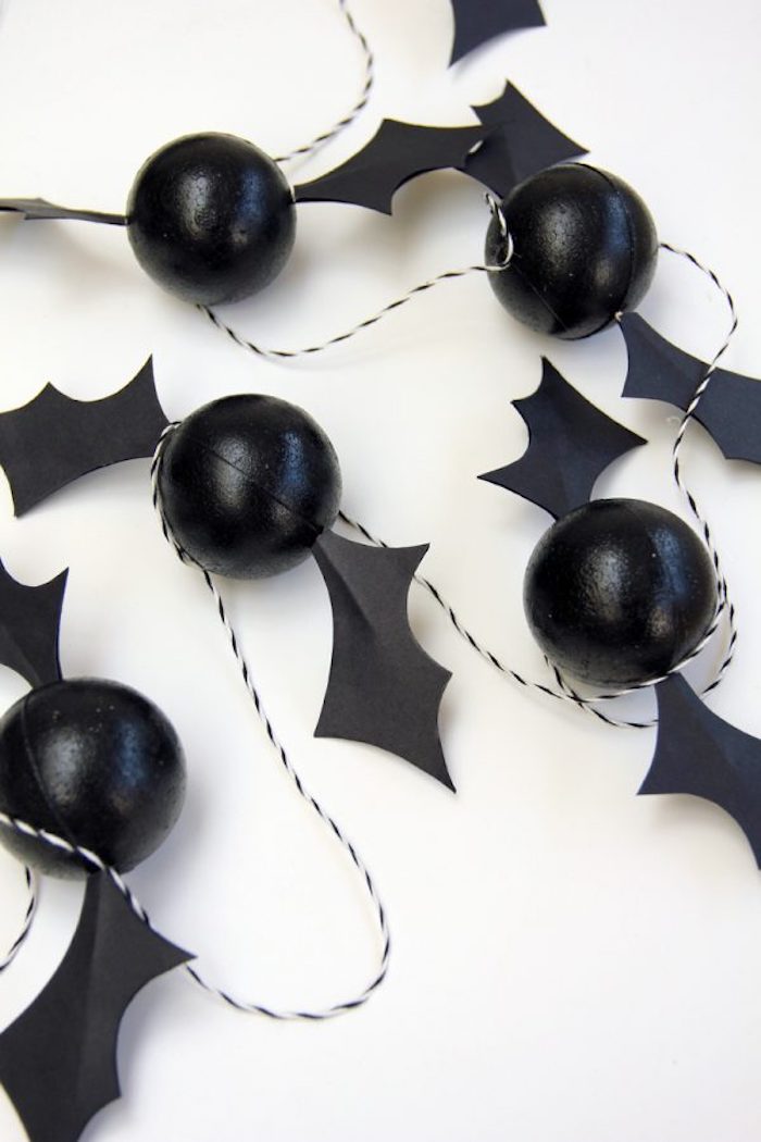 kleine schwarze fledermäussen aus kleinen schwarzen bällen und mit schwarzen flügeln, eine dekoration mit kleinen fledermäusen