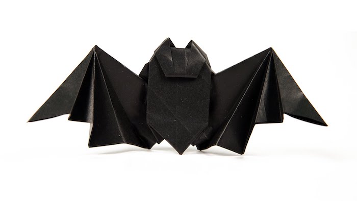 eine kleine diy origami fledermaus aus papier selber basteln, eine fledemaus mit schwarzen flügeln und schwarzen ohren aus papier 