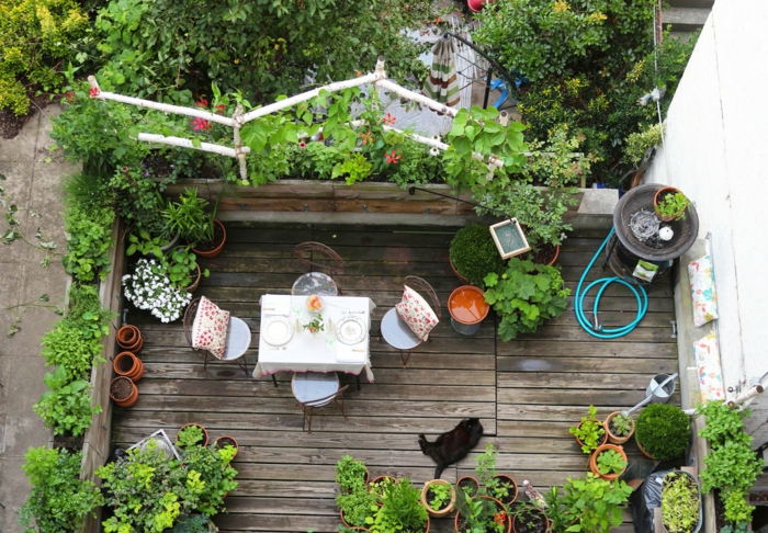 viele Terrassenpflanzen, ein kleiner Tischlein mit vier Stühlen, braune Terrassendiele