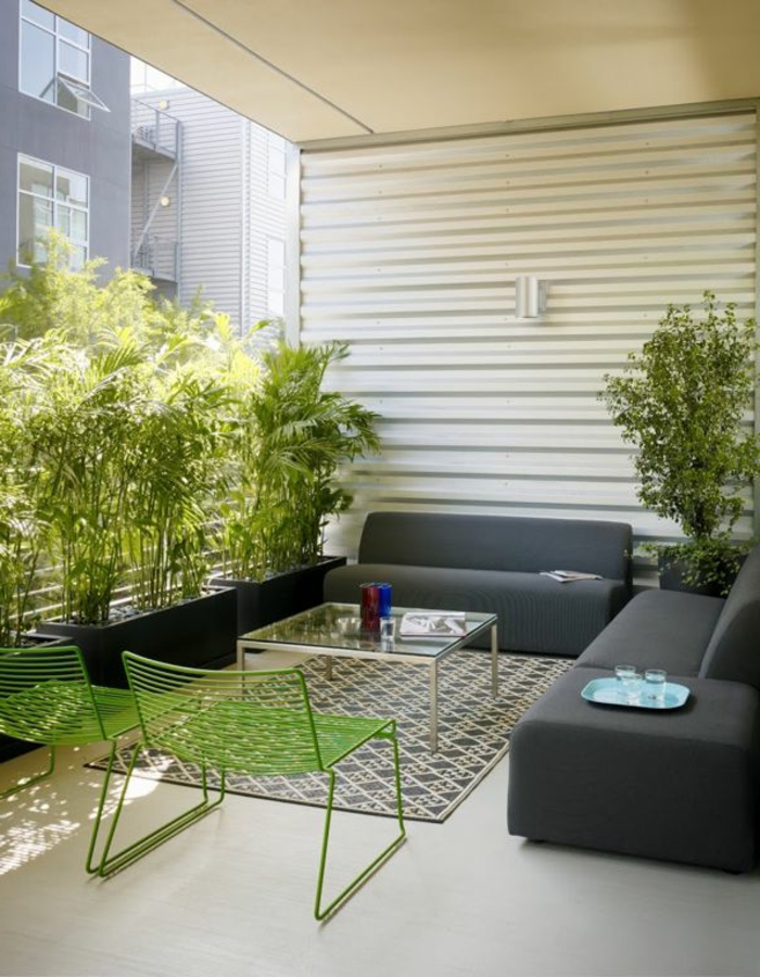 eine Terrasse mit Terrassenpflanzen in schwarzen Pflanzenkübel, graue Loungemöbel