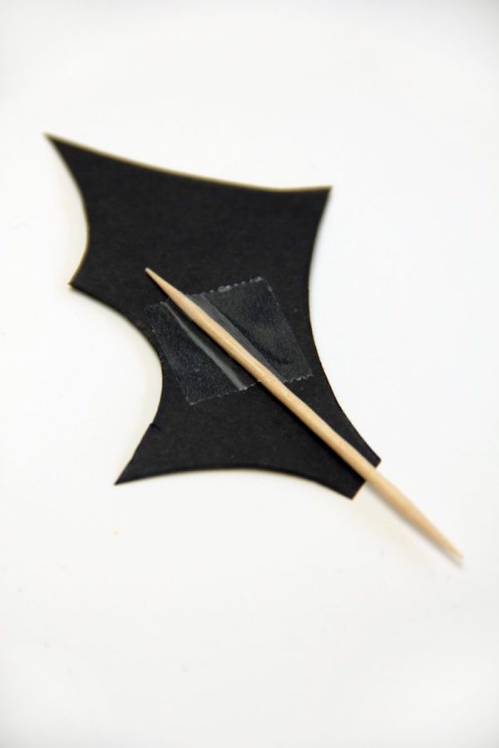 ein kleiner gelber zahnstocher mit einem schwarzen fledermaus flügel aus papier, eine fledermaus selber machen