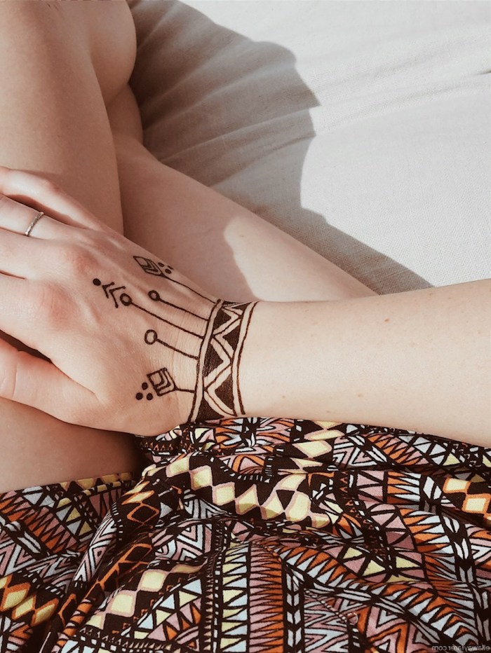 henna muster für anfänger, frau mit kleinem temporärem tattoo am handgelenk, geometrische motive
