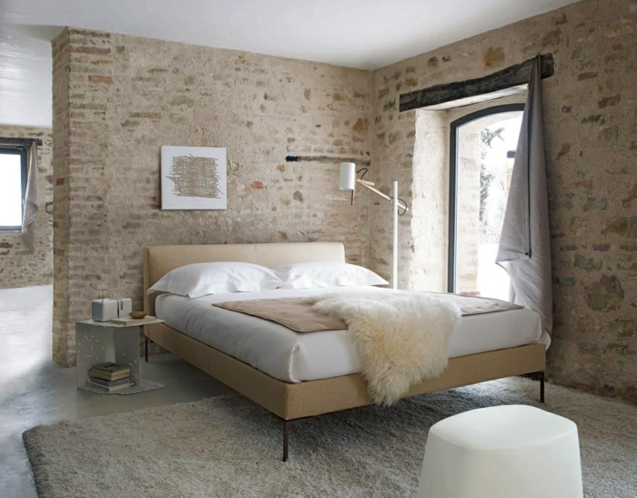 ein Schlafzimmer im Altbau, moderne Zimmer mit Naturstein Optik Wände, weißes Bett