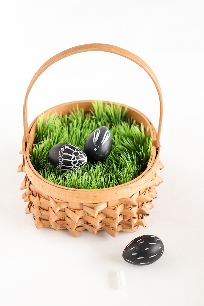 Schwarze Ostereier mit weißem Stift verziert, auf künstlichem Gras, schöner Osterkorb