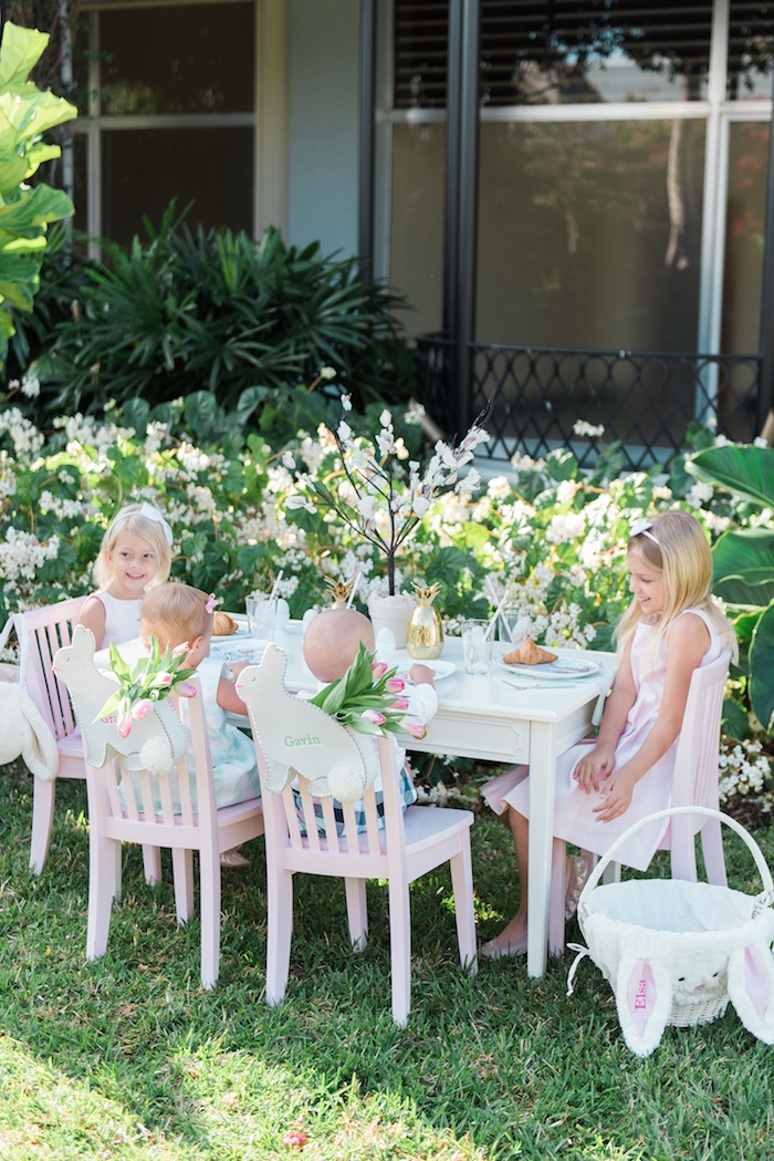 Osterparty für Kinder im Garten, Tulpensträuße und Osterhasen, kleine Kinder haben Spaß