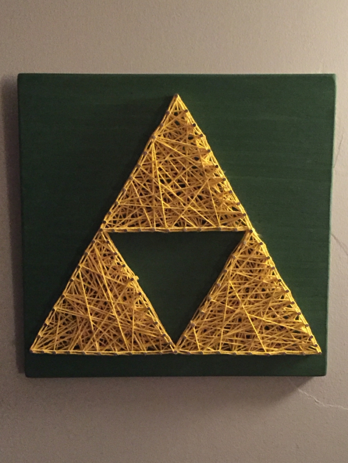 ein grünes Brettchen, eine Fadengrafik Anleitung, drei Dreiecken wie Pyramide