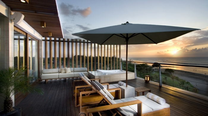 eine wunderbare Terrasse am Strand, zwei weiße Liegestühle mit Sonnenschirm in der Mitte