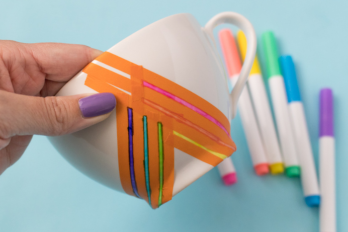 Bunte Streifen mithilfe Klebeband auf eine weiße Tasse aufzeichnen, Permanentmarker benutzen