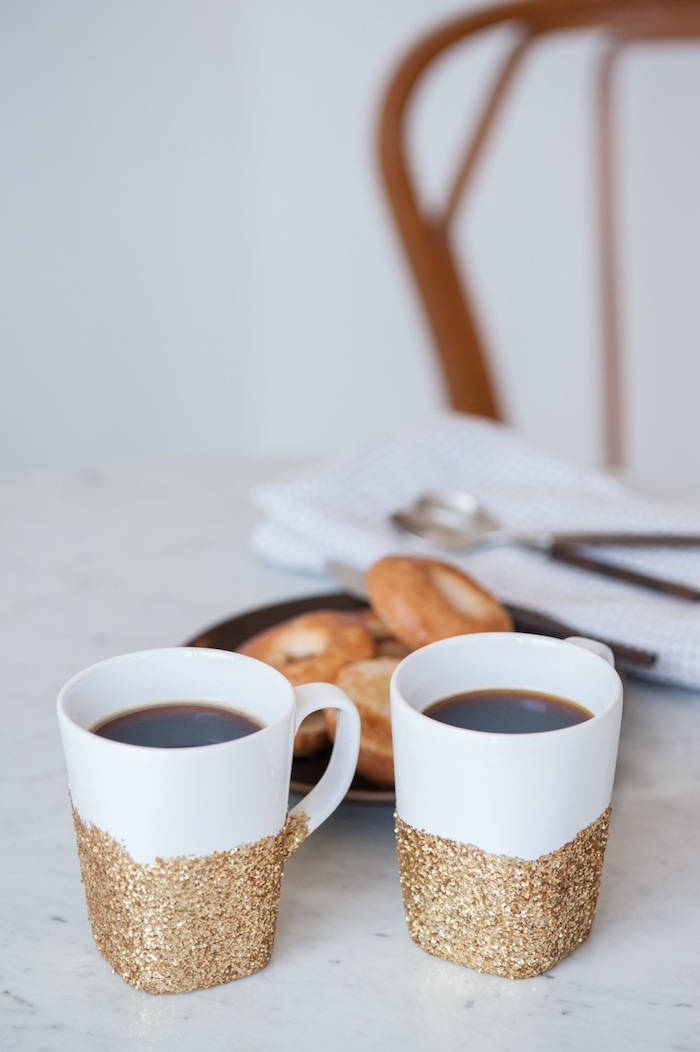 Weiße Tassen mit goldenem Glitzer verziert, Kaffee und Donuts genießen