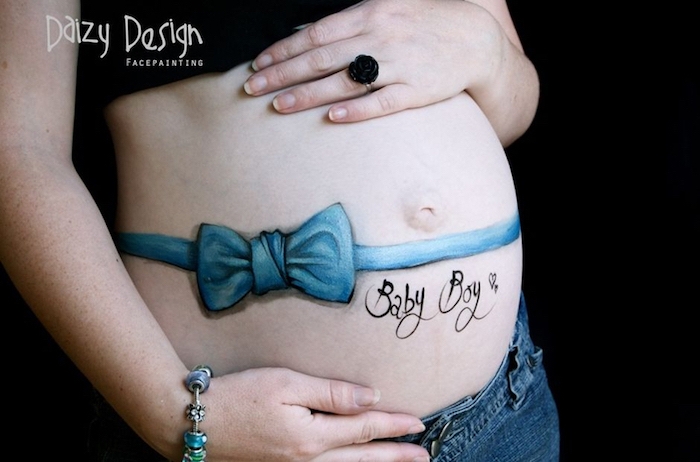 hand mit einem blauen armband, babybauch fotos, schwangere frau mit einem großen bemalten babybauch mit einer blauen schleife