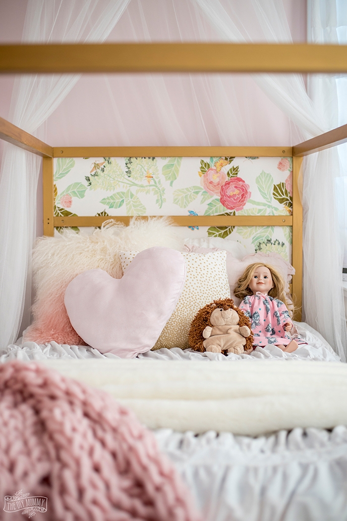Babybett in Rosa mit Blumenmuster, Puppe mit blonden Haaren und Kuscheltier Igel, Herzkissen und kuschelige Decke