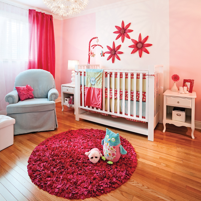 Babyzimmer Deko, roter Teppich und Papierblumen an der Wand, weißes Babybett und blauer Sessel