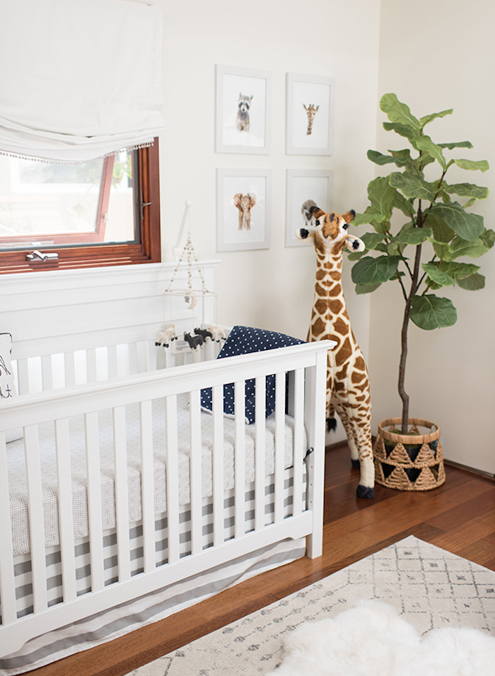 Babyzimmer in Weiß, Kuscheltier Giraffe neben dem Babybett, grüne Pflanze