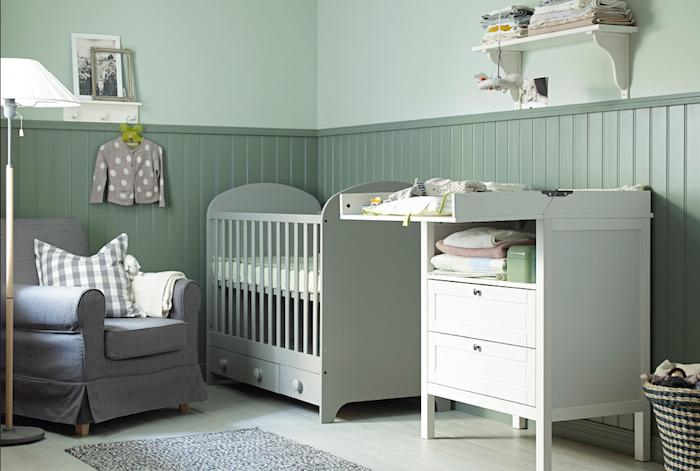 Babyzimmer in Grün, grauer Sessel, weße Möbel, weiße Stehlampe, Bilder an der Wand