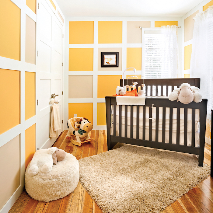 Babyzimmer in Gelb, dunkelblaues Holzbett, süße Kuscheltiere und Mobile