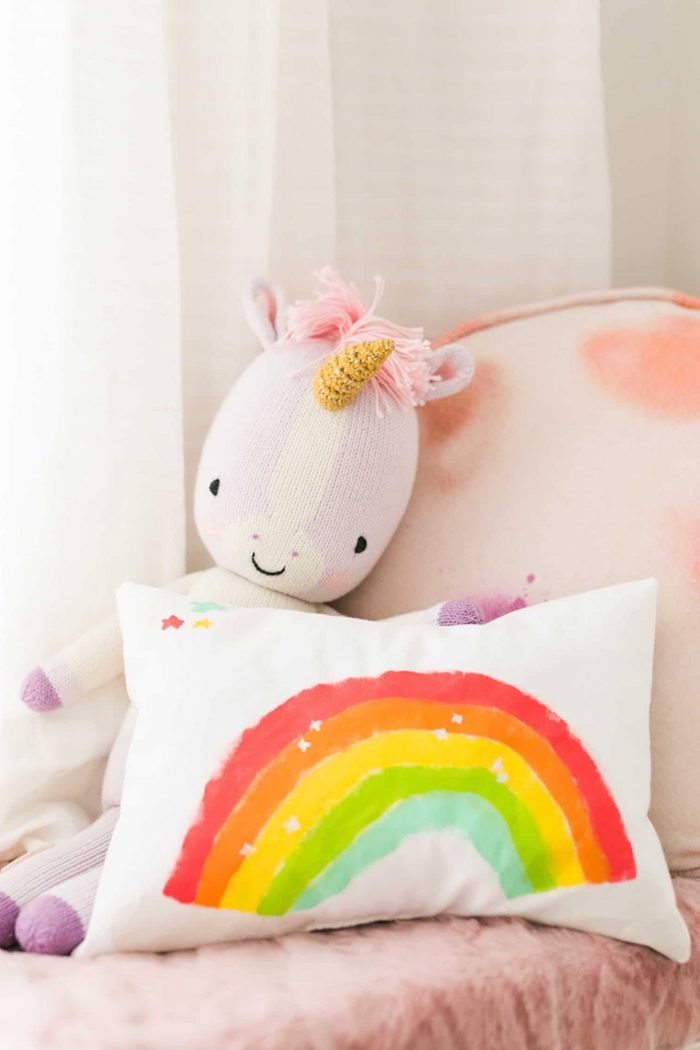 Babyzimmer Deko Ideen, weißes Kissen mit Regenbogen, Einhorn Plüschtier, rosa Bettwäsche 