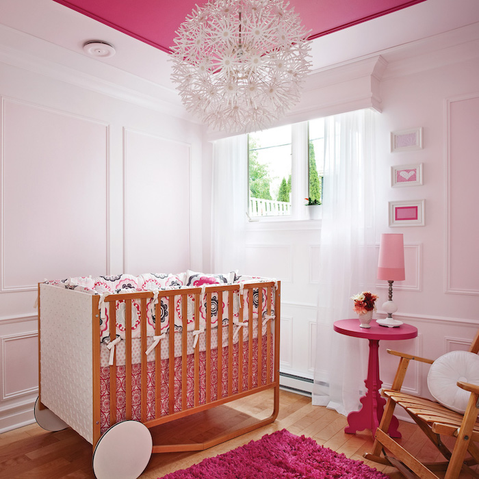 Mädchenzimmer für Baby, Holzbett mit Rollen, verspielter kronleuchter, violetter Teppich und Tisch