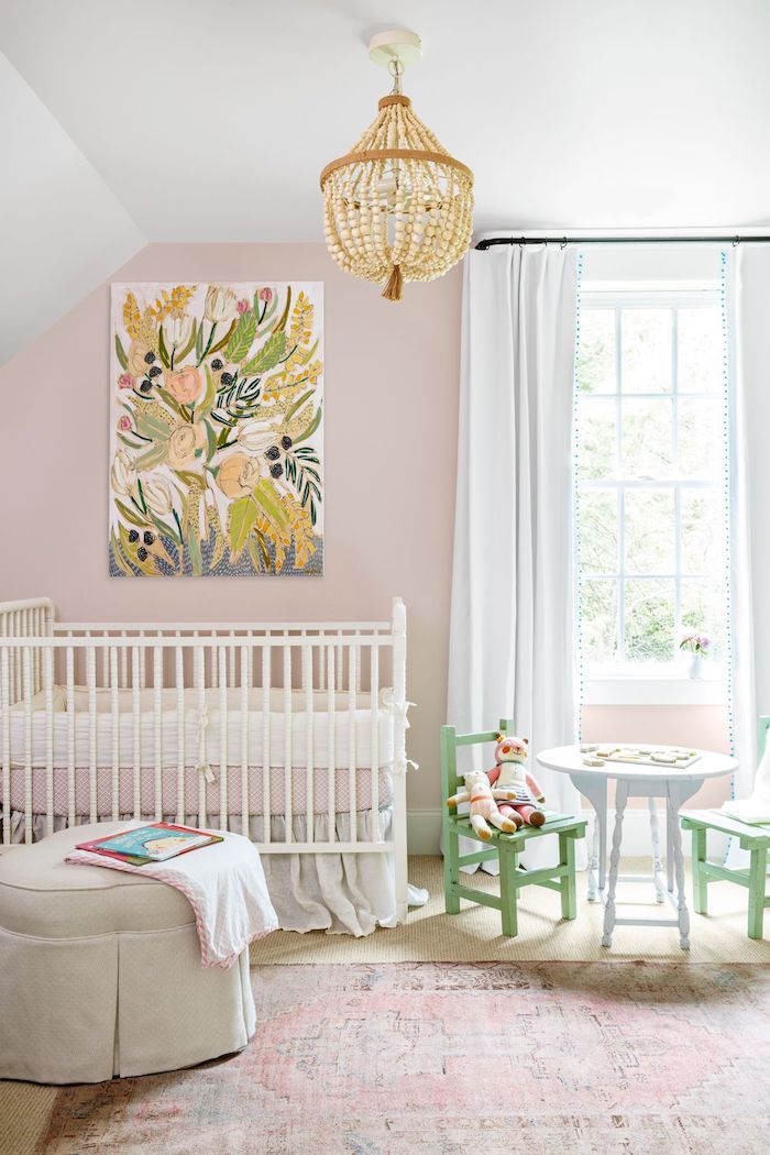 Babyzimmer in zarten Pastellnuancen, kleiner Tisch mit grünen Stühlen, weißes Babybett, Gemälde an der Wand