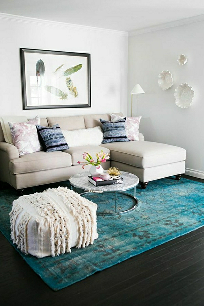 blauer Teppich, beiges Sofa, kleiner weißer Hocker, runder Tisch, Wohnzimmer gestalten