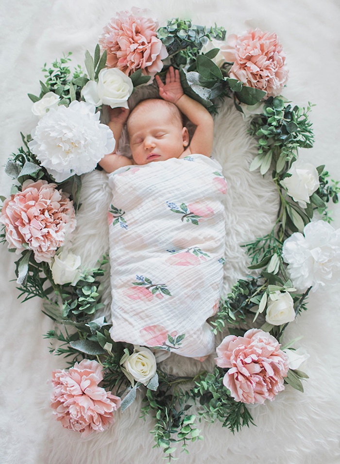 Süßes schlafendes Baby, Decke mit Blumenmuster, Kranz aus echten Blumen 