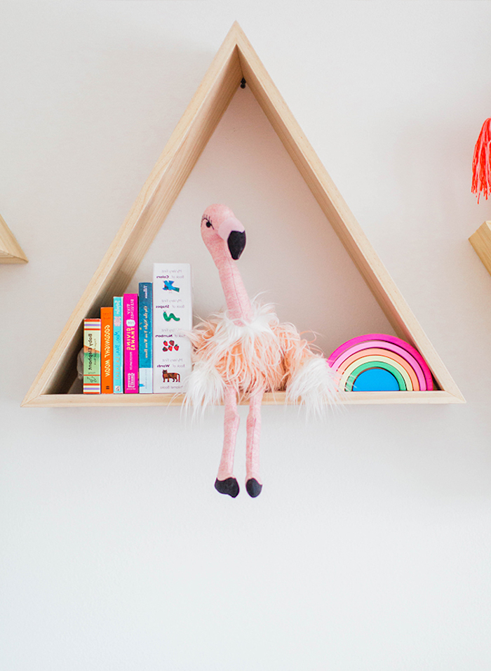 Dreieckiges Holzregal an der Wand, Plüschtier Strauß, Kinderbücher und kleiner Regenbogen