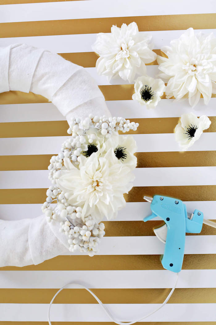 Türkranz selber machen, weiße Chrysanthemen mit Heißkleber befestigen, Frühlingsdeko für die Haustür