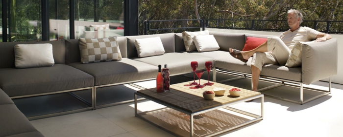 terrassenumrandung mit sofa und möbel, schöne idee, mann sitzt auf der eigenen terrasse und genießt den tag