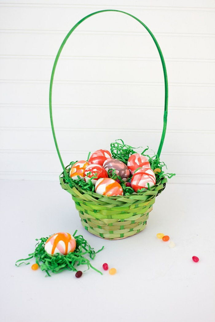 grünes Körbchen mit künstlichem Gras, bunte Eier, Ostereier dekorieren