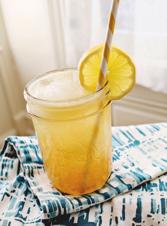 eine große blaue decke, ein glas mit einer gelben limonade mit eis und zitronen und einem gelben strohhalm, eine zitronenlimo selber machen