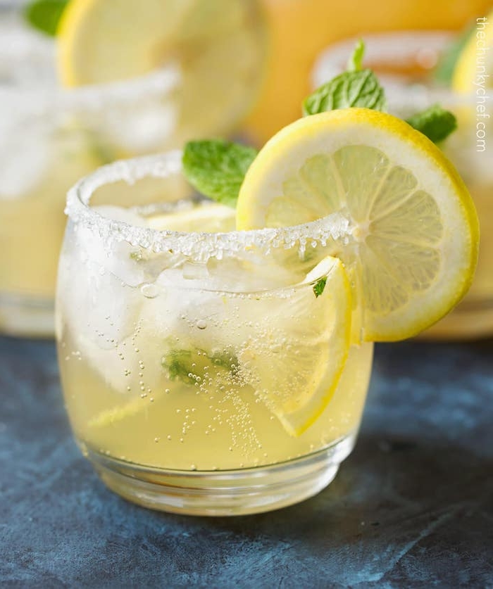 limonade rezept, ein glas mit zucker und einer selbstgemachten amerikanischen gelben limonade mit eis, gelben zitronen und minze mit grünen blättern
