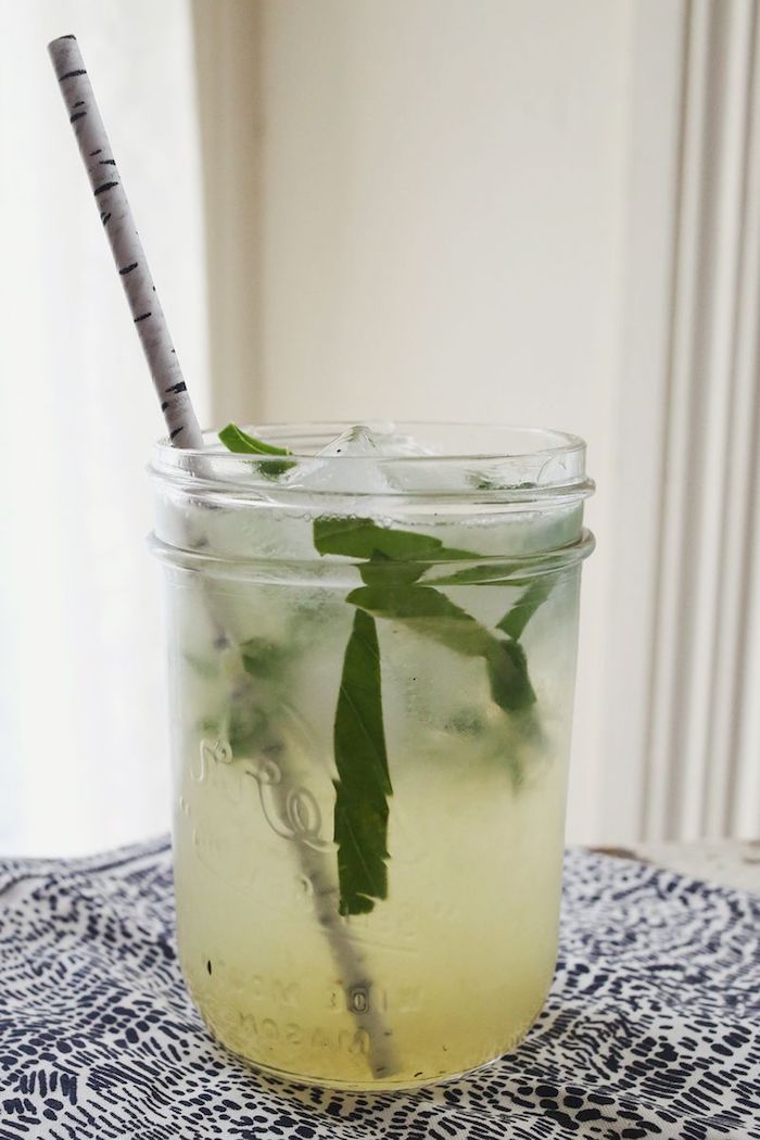 eine weiße birke, ein glas mit einem weißen strohhalm und einer hausgemachten limonade mit eis und mit minze mit grünen blättern, eine zitronenlimo selber machen