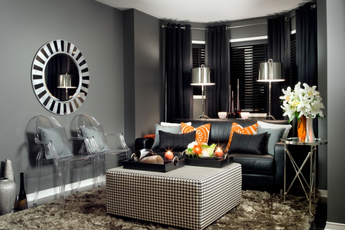 schwarzes Sofa, orange und blaue Kissen, karrierter Tisch, ein runder Spiegel, kleine Wohnung einrichten