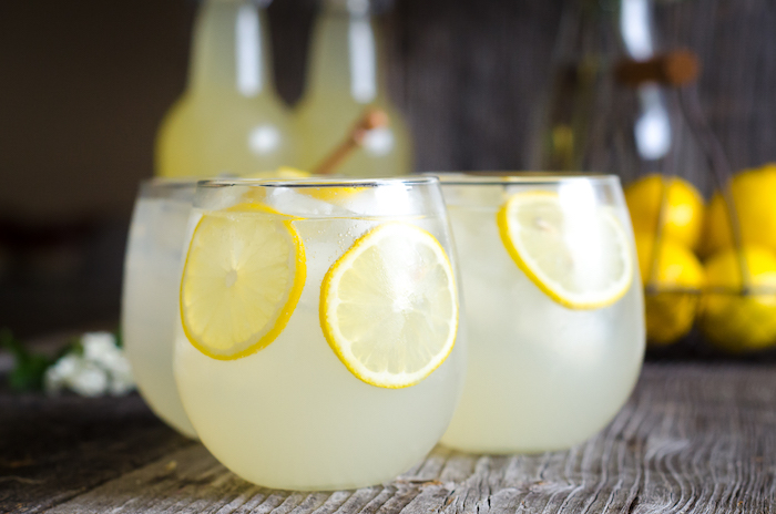drei kleine gläser mit eis und kleinen gelben zitronen, eine hausgemachte limonade, eine erfrischungsgetränk selber machen