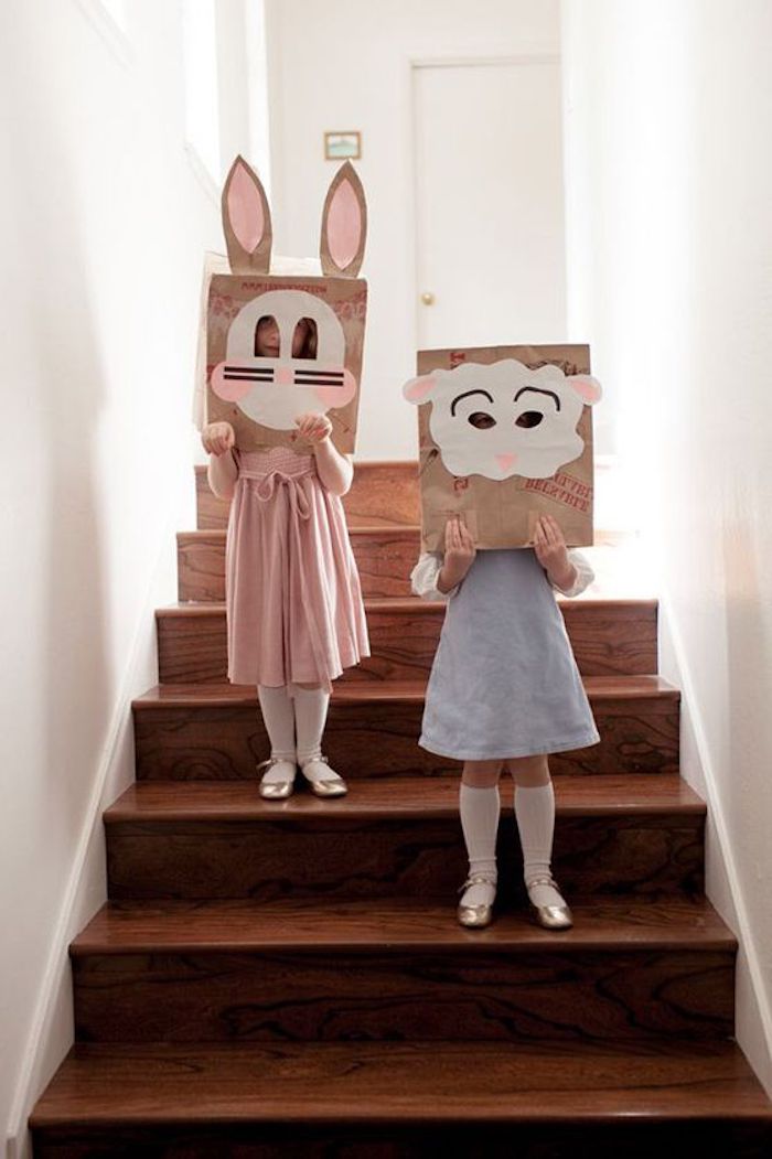 zwei mädchen mit blauen und pinken kleidern, eine braune treppe aus holz und weiße wände, hasen masken mit pinken hasenohren aus papier, lustige osterbilder für kinder