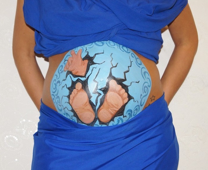 junge schwangere frau, ein großer bemalter babybaauch mit einem blauen ei und einem baby und kleinen sternen, kleid für babybauch shooting