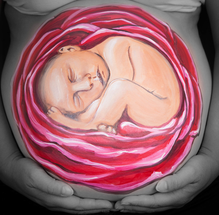 eine große rote rose und ein schlafendes baby, eine schwangere frau mit einem großen bemalten babybauch, babybauch shooting ideen