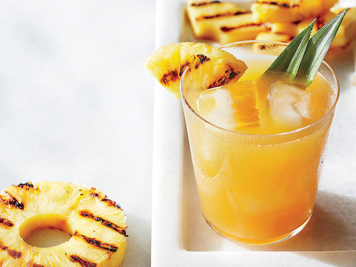 ein glas mit einer ananas und mit einer hausgemachten orangen limonade mit eis, eine erfrischungsgetränk selber machen, grüne blätter
