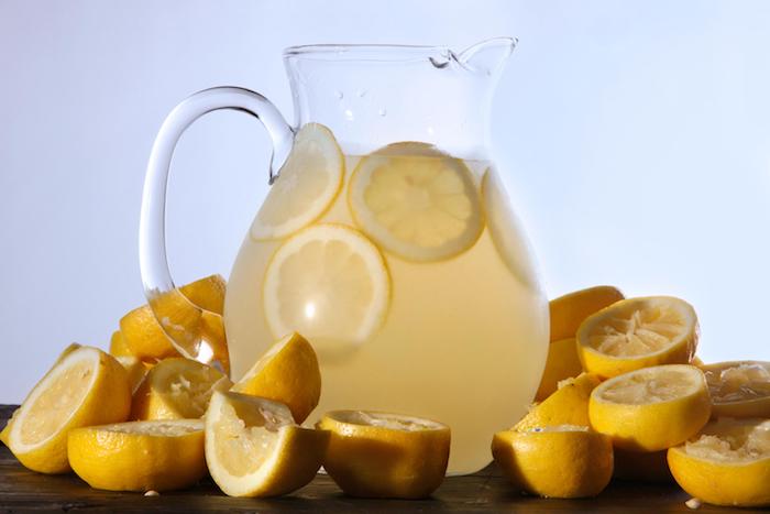 ein großer krug mit einer gelben hausgemachten amerikanischen limonade und mit vielen gelben zitronen, eine amerikanische zitronenlimonade selber machen