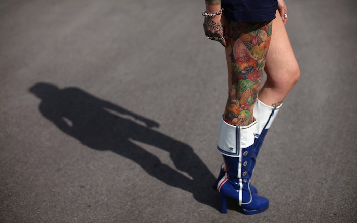 frisches tattoo, frau mit bunten tätowierungen am bein, blaue hohe stiefel, silberne ringe, hand tattoo