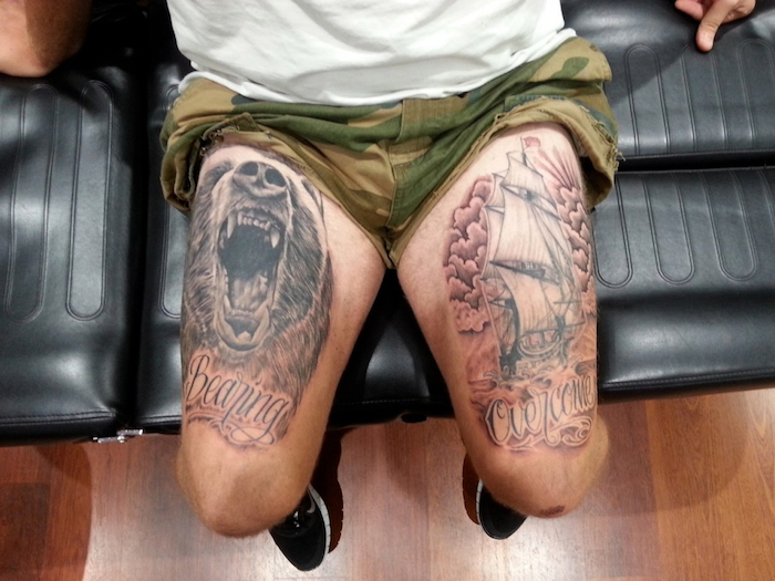frisches tattoo, mann mit realistischen tätowierungen an den beinen, bär, schiff mit wolken und wasser