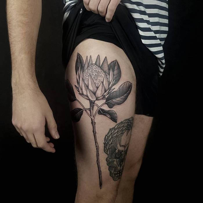 frisches tattoo mit blumen-motiv, große blume in schwarz und grau, schädel am oberschenkel