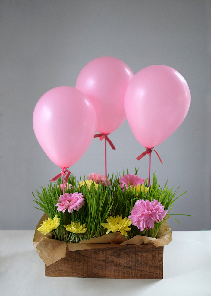 Schöne Geschenkidee zum Muttertag, rosa und gelbe Gerbera im Gras, drei rosa Ballons