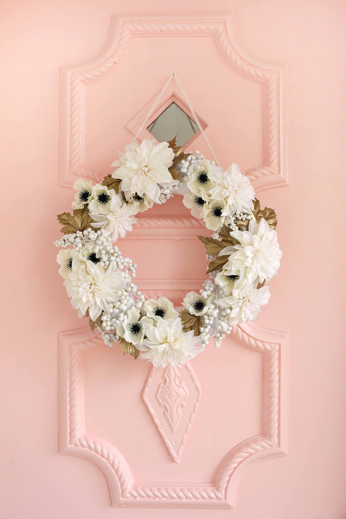 Türkranz mit weißen Blüten und goldenen Blättern, rosa Haustür, Frühlingsstimmung zu Hause