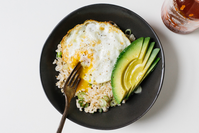 frühstücksideen gesund, ein schwarzer teller, reis mit avocado und ei, gesund frühstücken