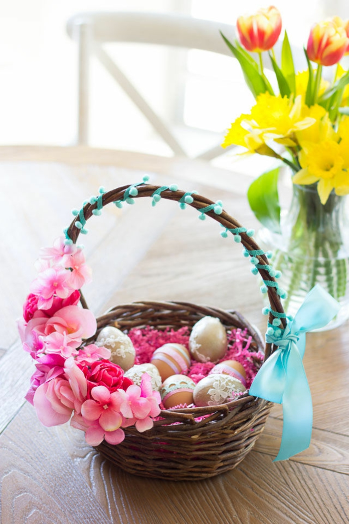 kleine Ostergeschenke, bemalte Ostereier in Rattan Korb mit rosa Blumen dekoriert