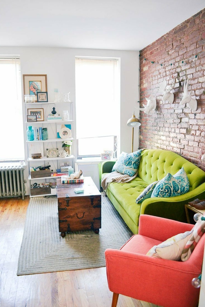 weißes Regal, grünes Sofa, roter Sessel, grauer Teppich, Kisten als Tisch, Wohnzimmer gestalten