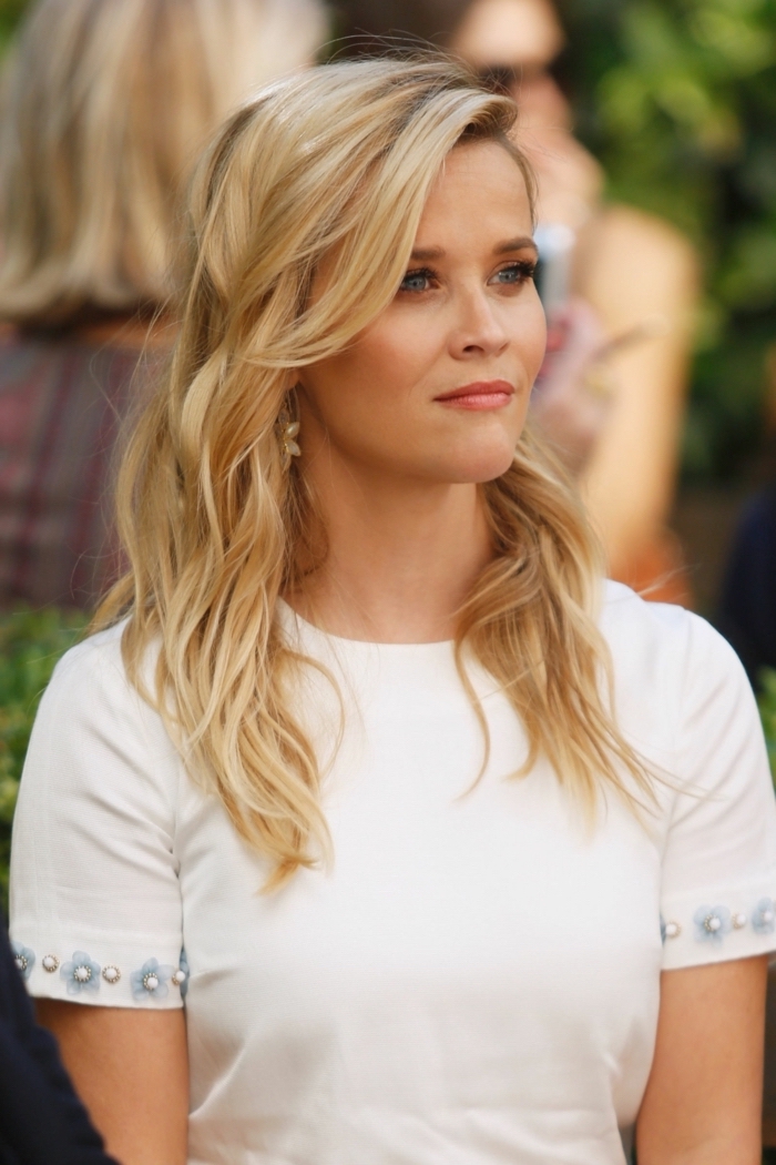 Reese Witherspoon Langhaarfrisur, blonde Haare mit seitlichem Pony, weiße Bluse, kleine Blüten und Perlen an den Ärmeln