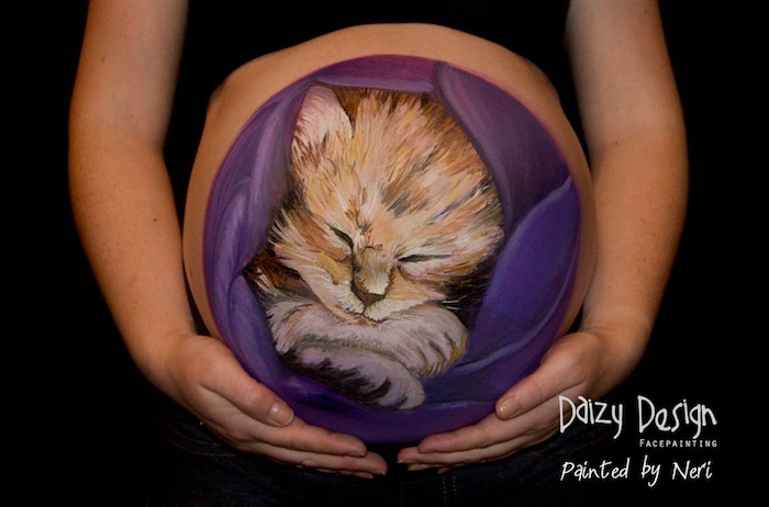 schwangere frau mit einem bemalten bauch, ein bild mit einer schlafenden katze
